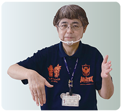手話通訳・鈴木さんが左手の手のひらを内側に立て、右手は手のひらを内側に胸の前まで下げた写真