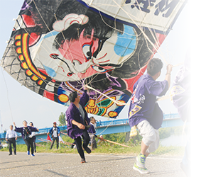 五郎組の大凧と網を引っ張る法被姿の男性2人の写真。令和元年白根大凧合戦フォトコンテスト佳作作品「それ引け」