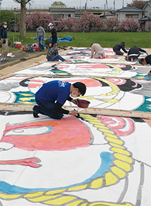 弁慶組の人たちが大凧に色を塗っている写真