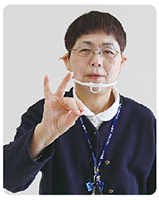 手話通訳者・鈴木さんが胸の前で親指に人差し指と中指をくっ付けている写真