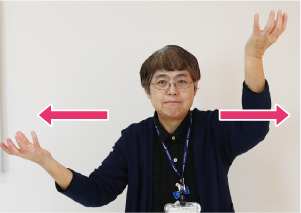 手話通訳者・鈴木さんがその手を上下にさせながら左右に広げている写真